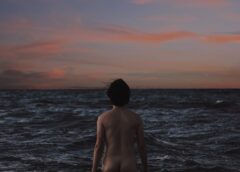 anonymous male nudist standing in waving sea
