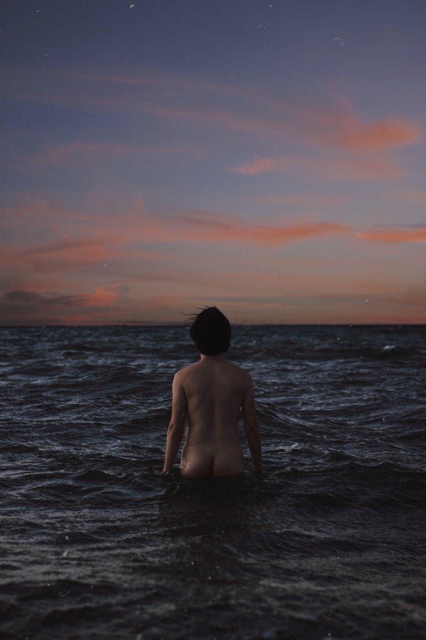 anonymous male nudist standing in waving sea