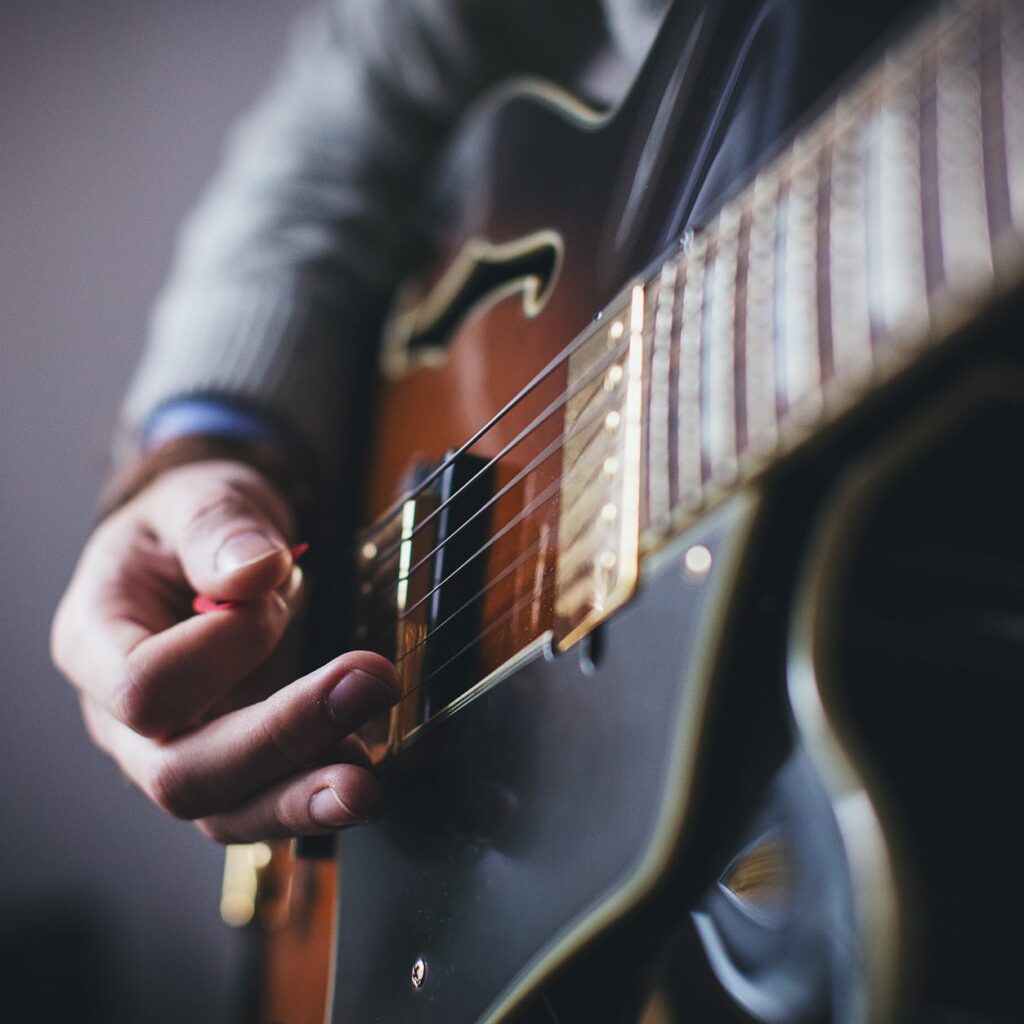 person playing brown and black guitar