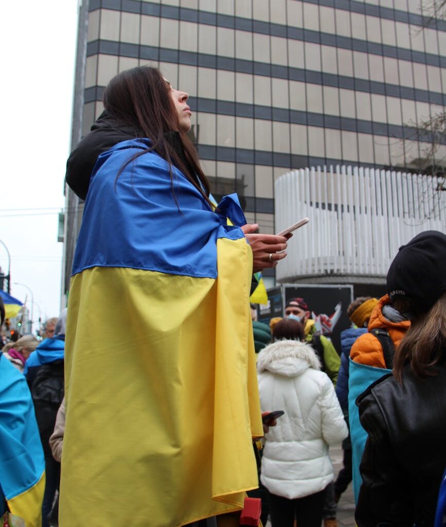 a woman wrapped in the national flag of ukraine during a peaceful protest in canada