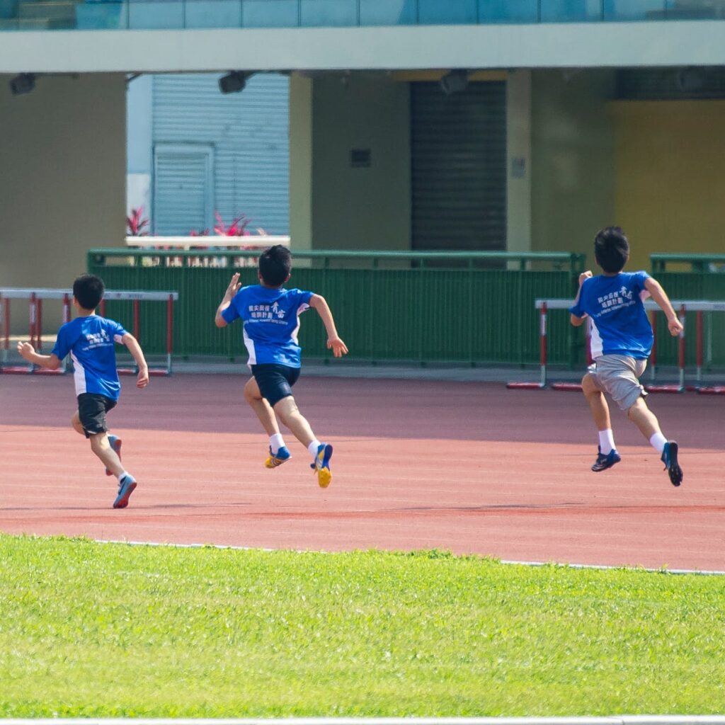 four boys running in track