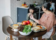 cheerful little asian boy having breakfast with kind grandmother at home