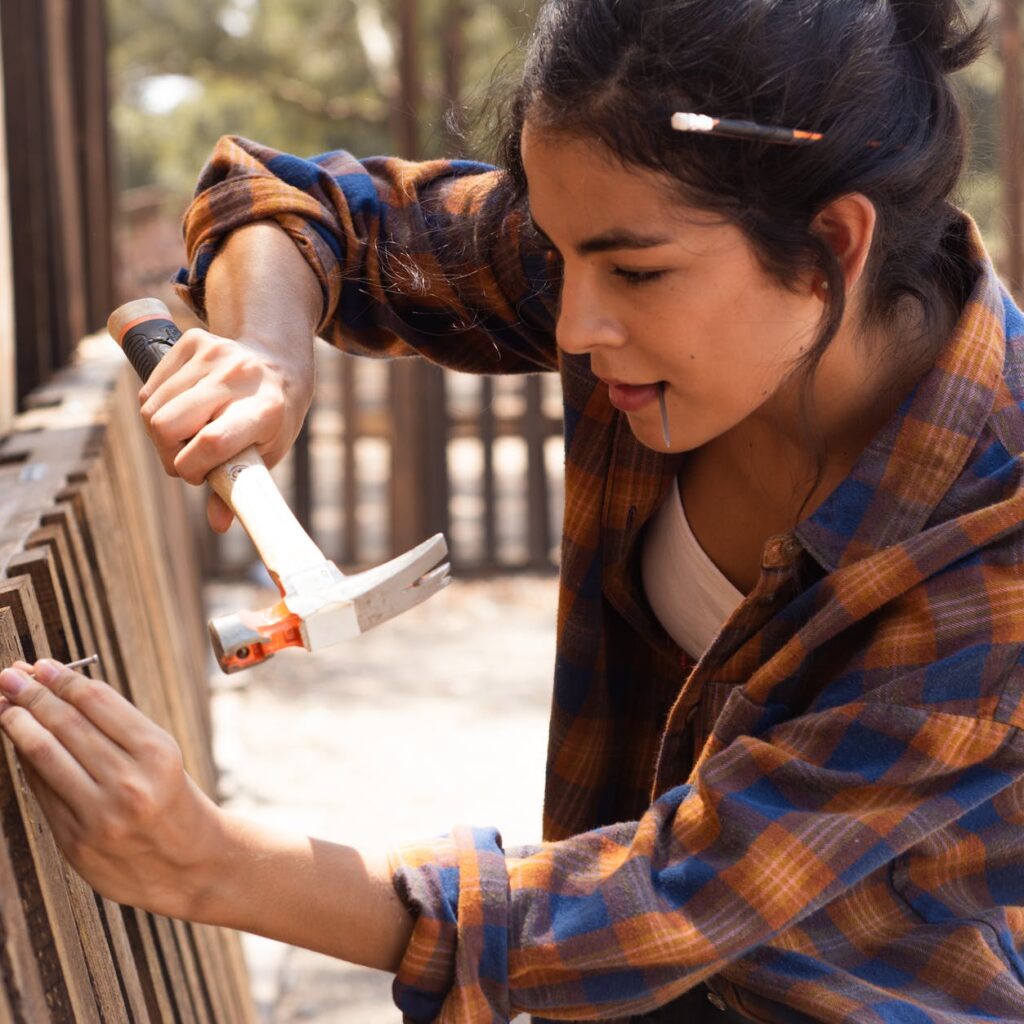 woman in brown scarf and blue and brown plaid dress shirt holding white plastic cup