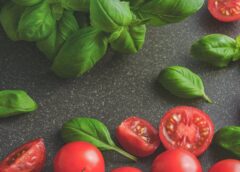 photography of tomatoes near basil leaves