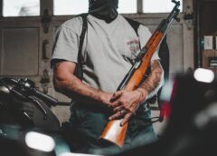 man wearing mask carrying rifle