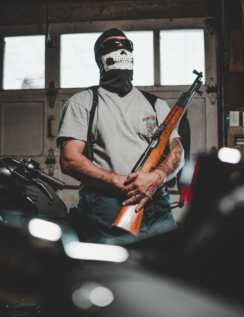 man wearing mask carrying rifle