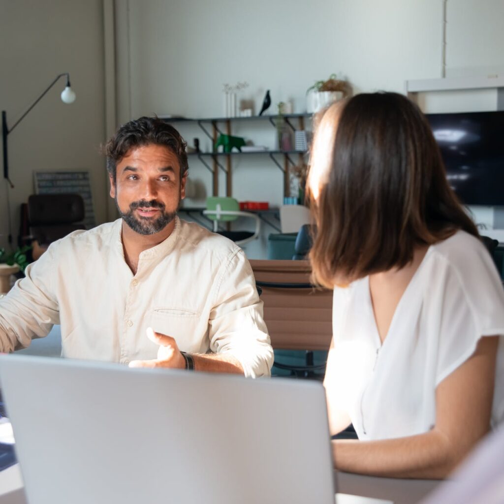 photo of a man with facial hair talking to a woman in the office