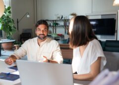 photo of a man with facial hair talking to a woman in the office