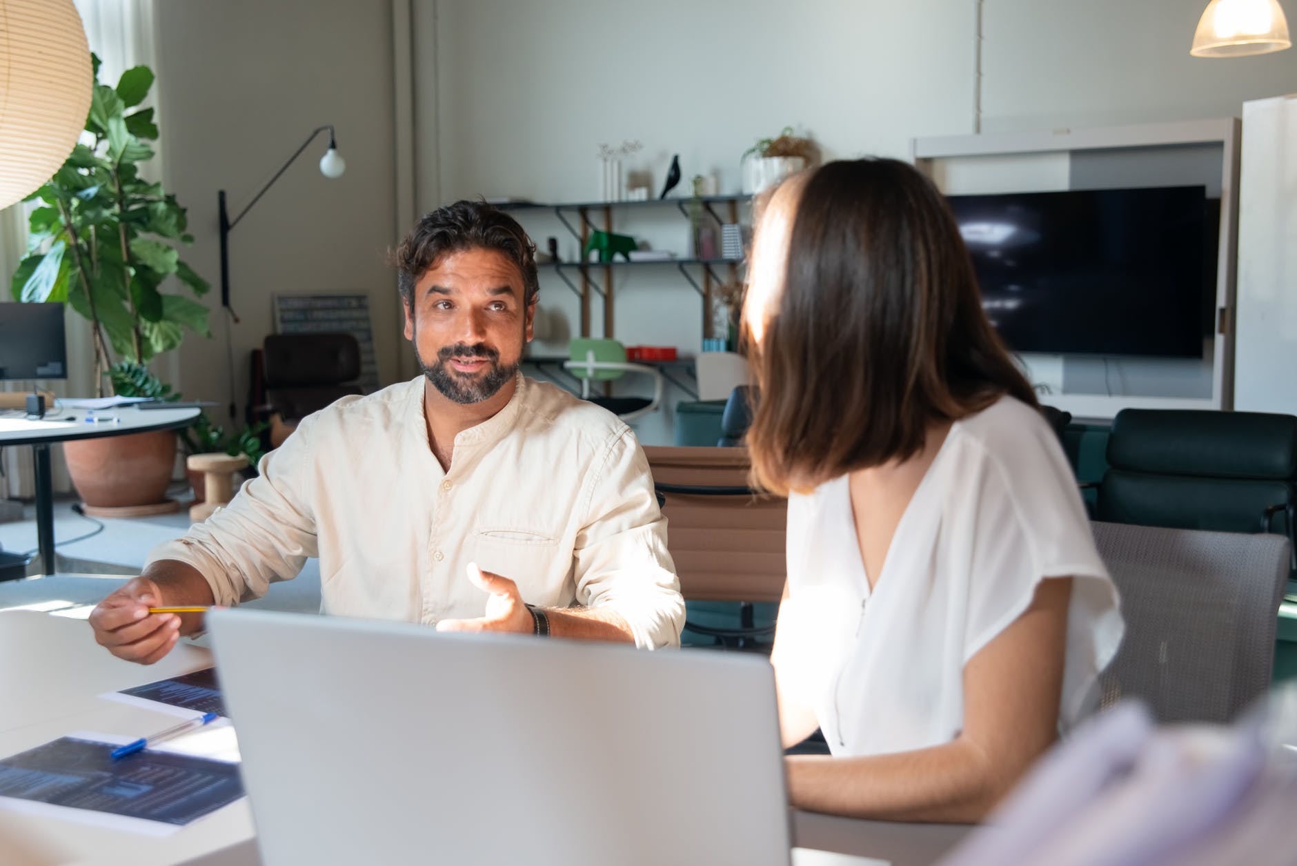 photo of a man with facial hair talking to a woman in the office