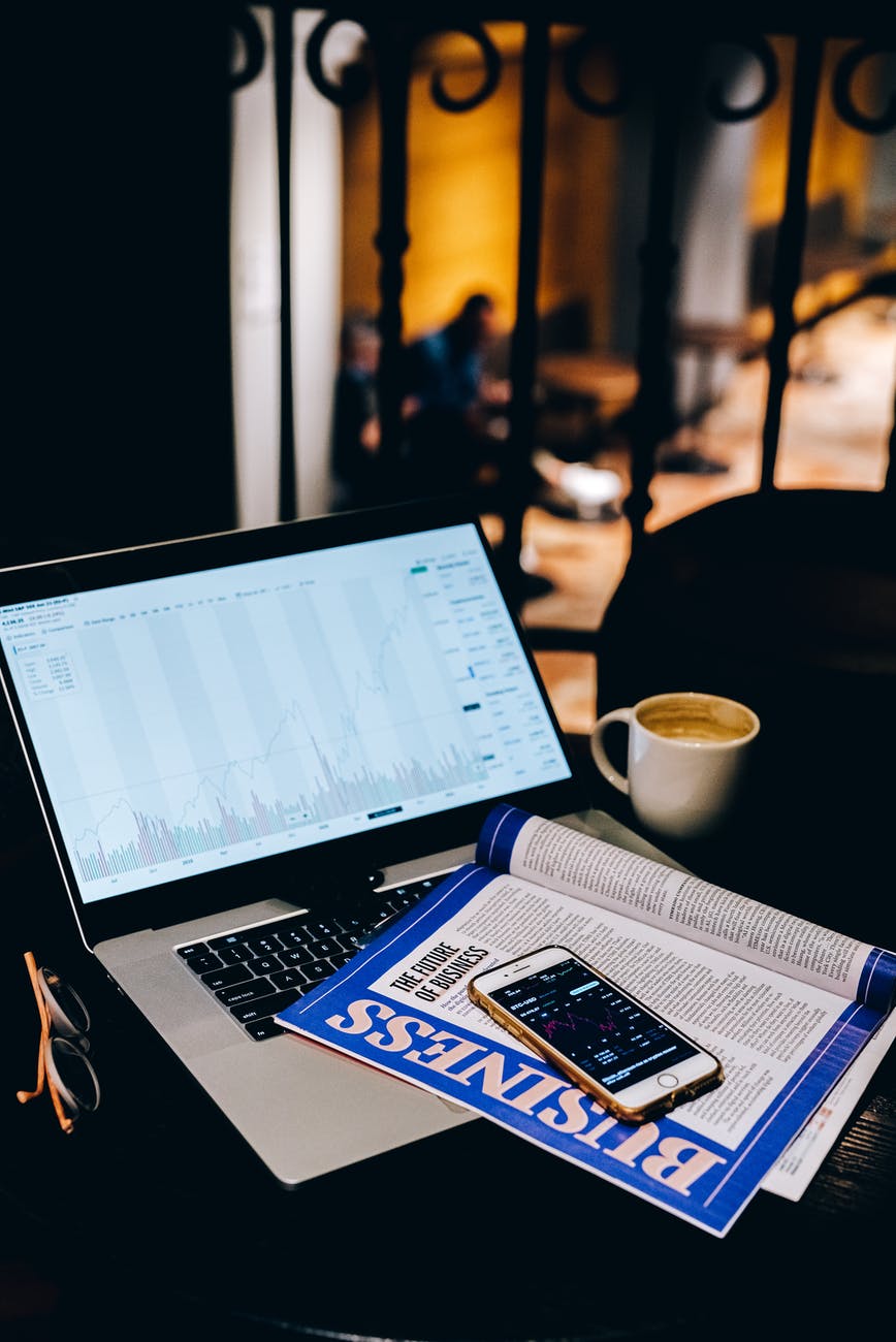 macbook pro beside white ceramic mug on table