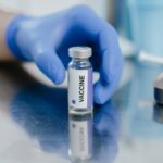 a person with blue gloves getting the vaccine vial