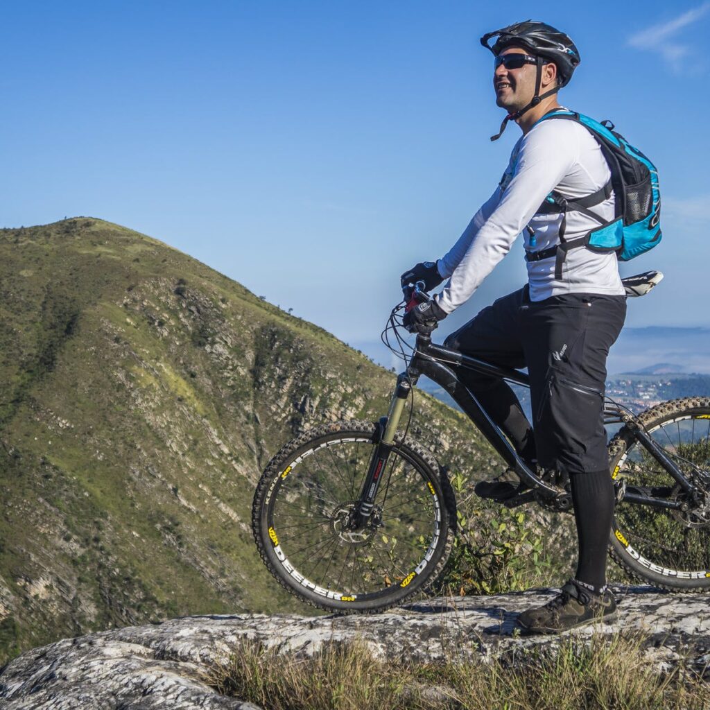 man with white shirt riding abicycle on a mountain