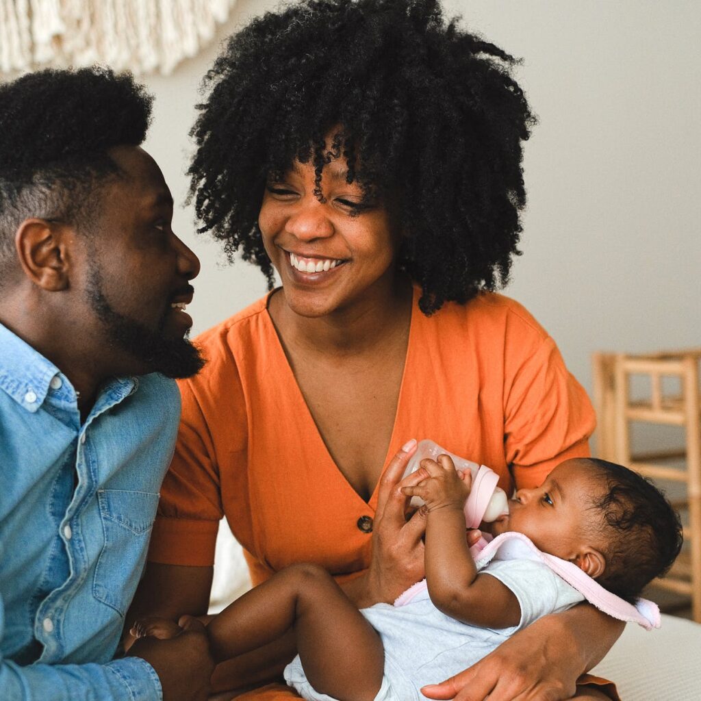 happy couple sitting on bed carrying a baby