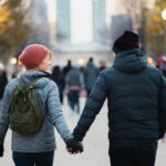 man and woman holding hands while walking at park