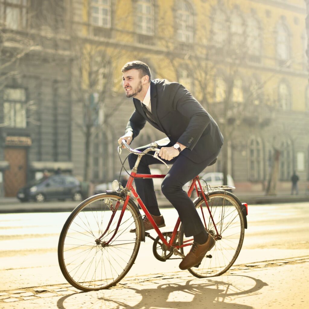 man in black suit riding bicycle down the street