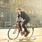 man in black suit riding bicycle down the street