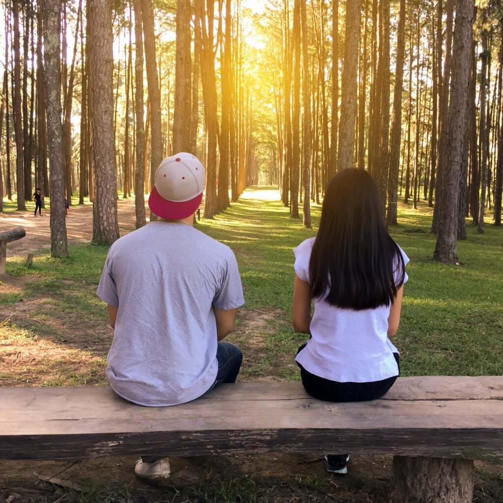 man and woman sitting on bench in woods