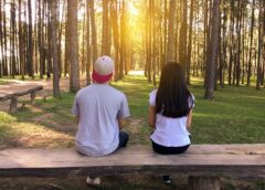 man and woman sitting on bench in woods