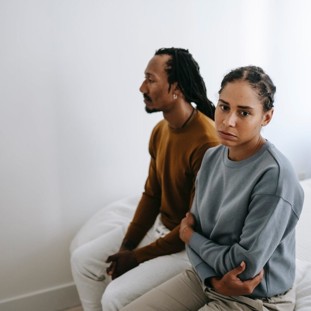 unhappy black couple sitting on bed together