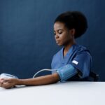 a healthcare worker measuring her own blood pressure using a sphygmomanometer