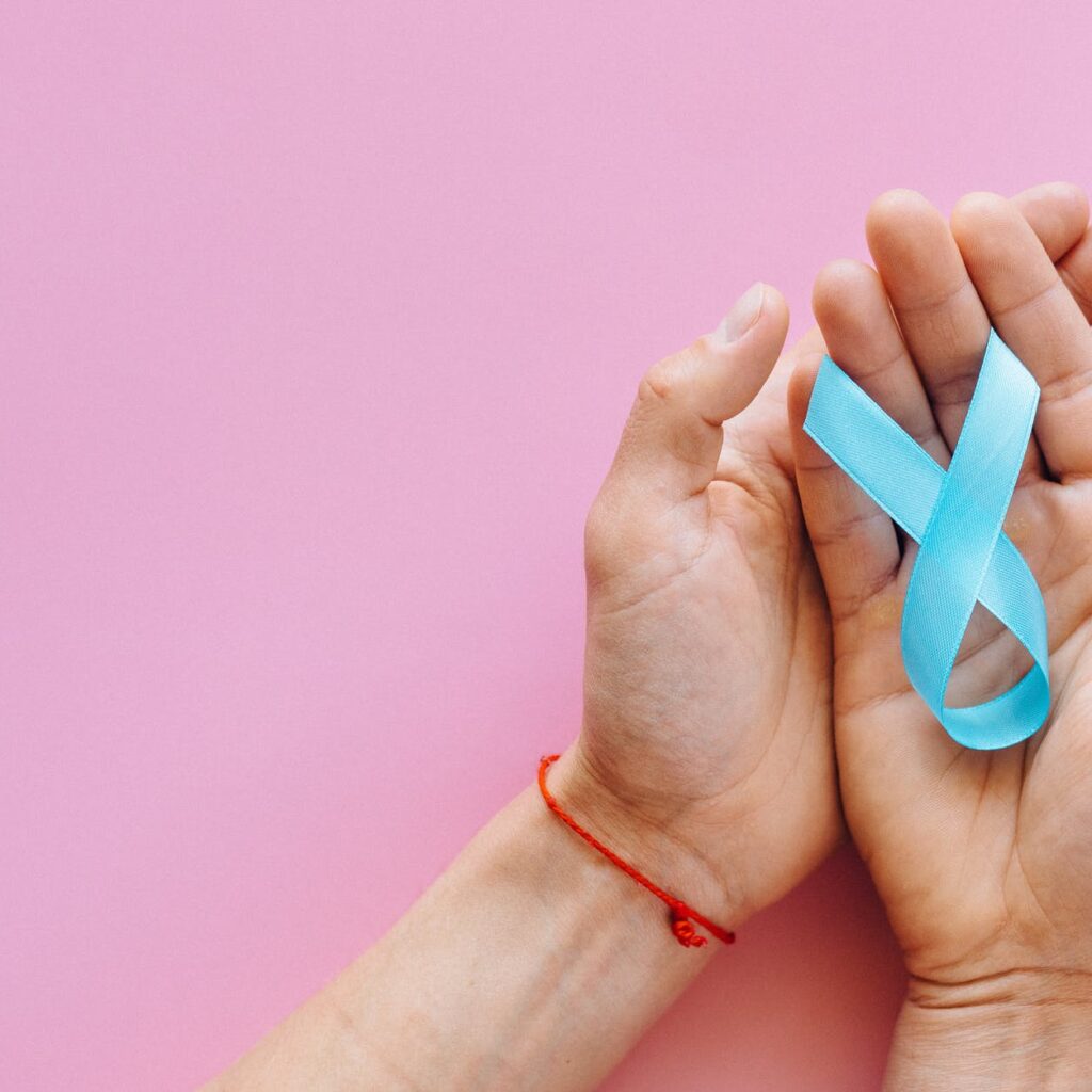 a person holding light blue ribbon on pink surface