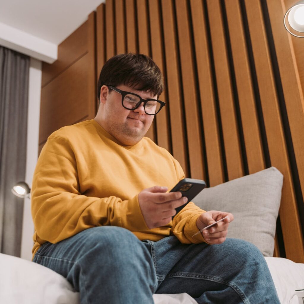 man in yellow sweater holding black smartphone and credit card