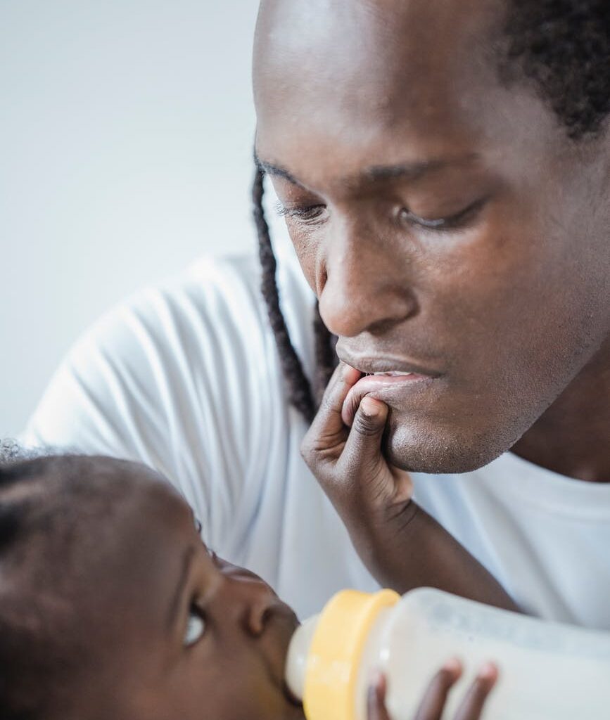 child touching his father s lips while drinking milk from a baby bottle