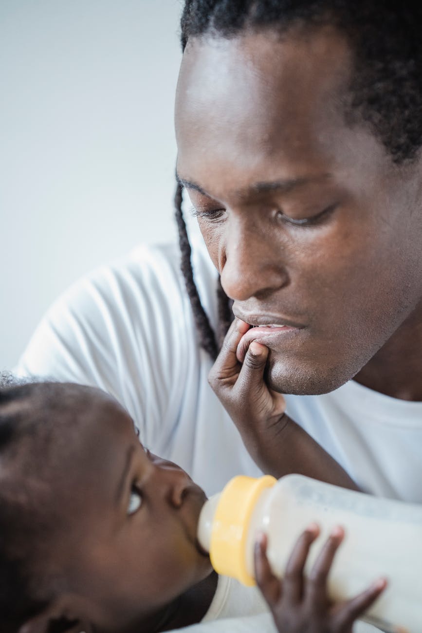 child touching his father s lips while drinking milk from a baby bottle