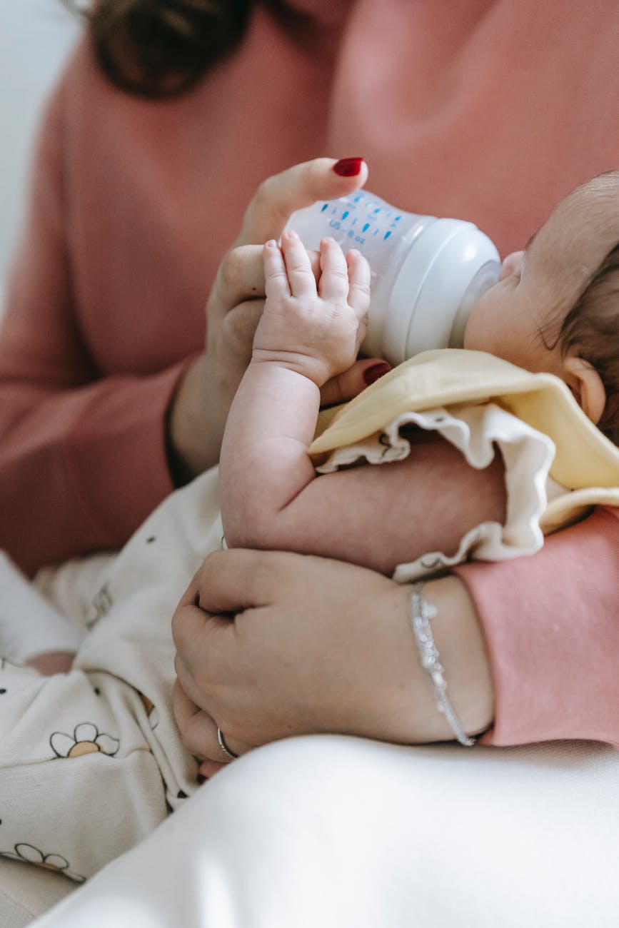 faceless mother feeding newborn baby