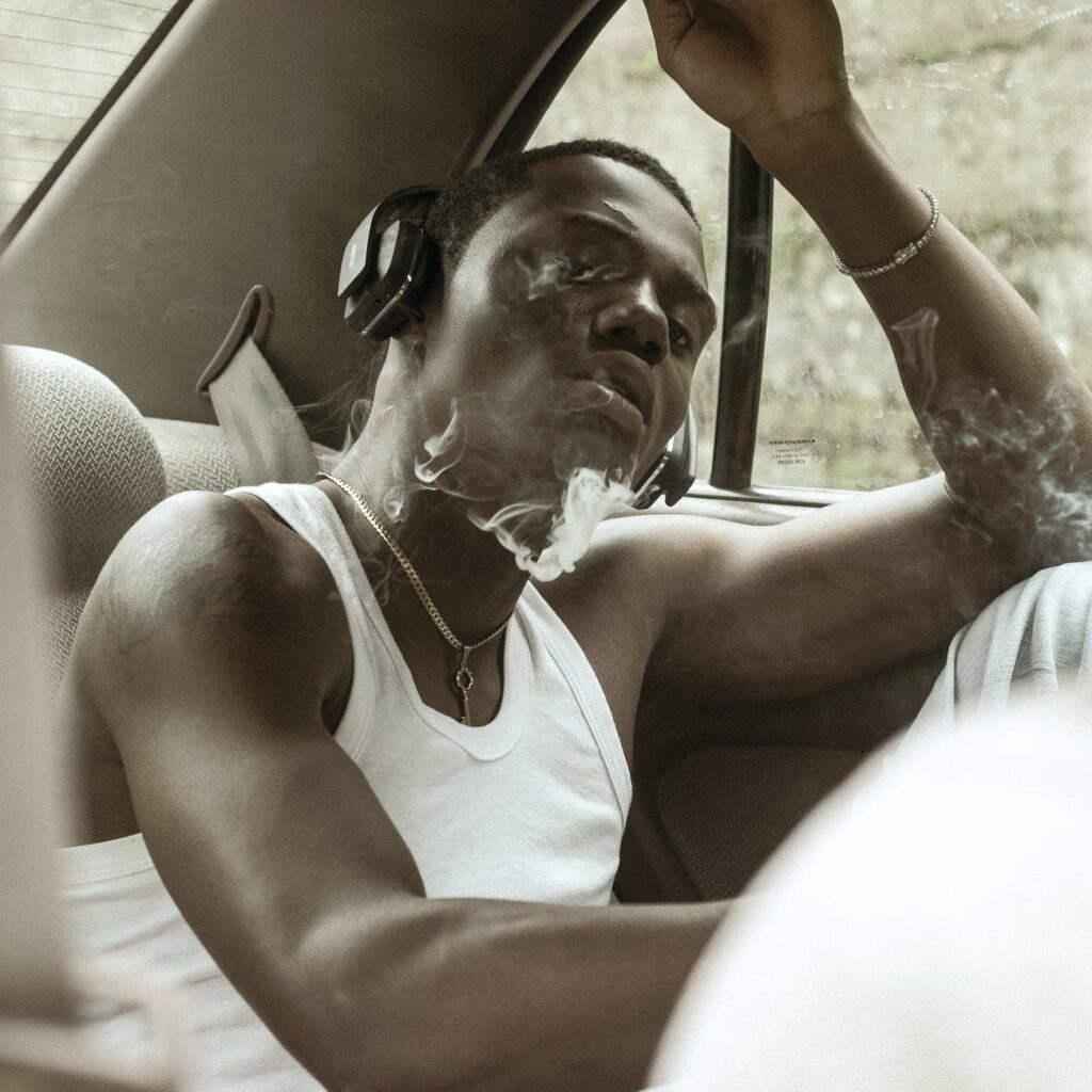 young man in headphones smoking in car