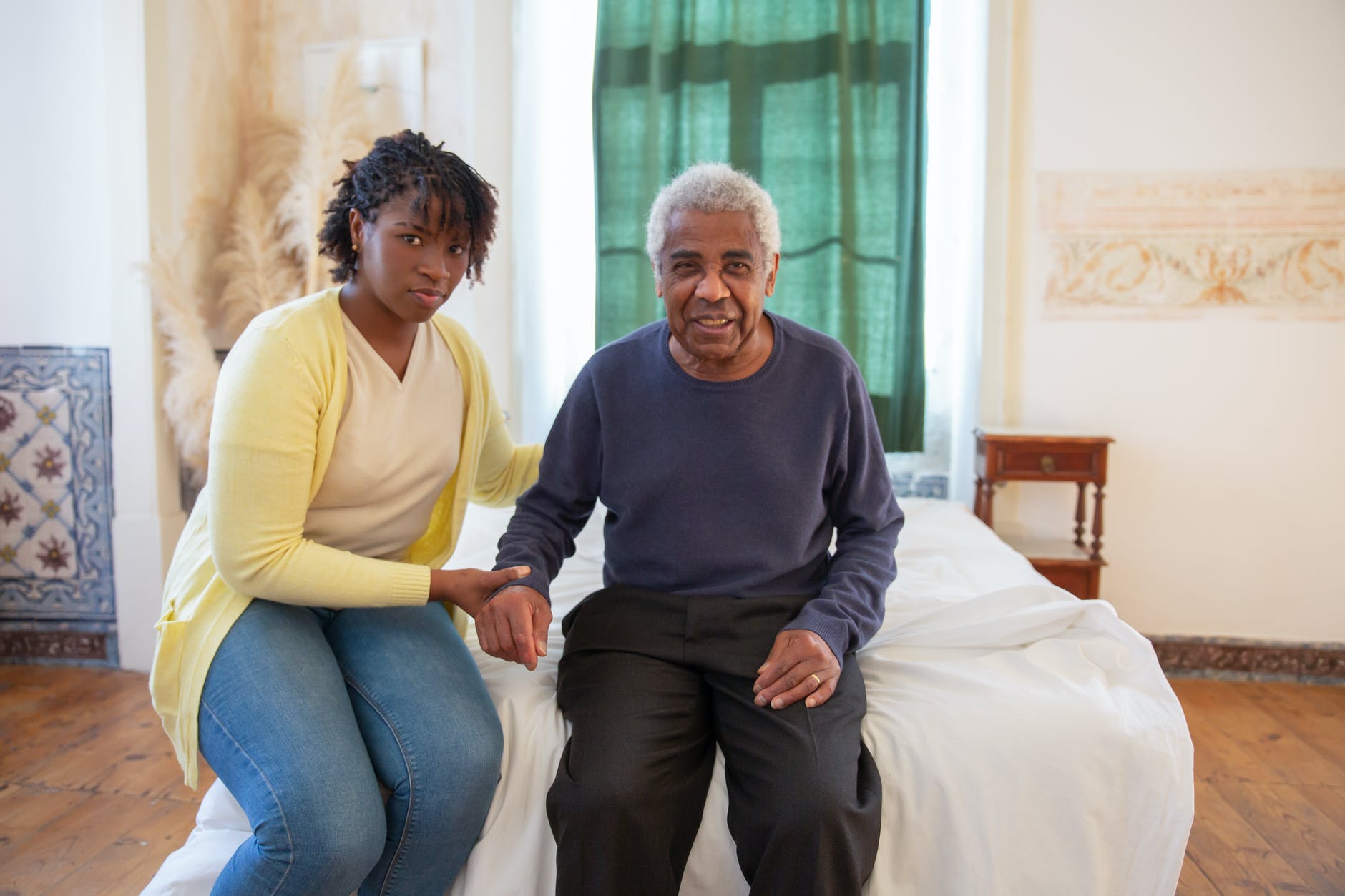woman and elderly man sitting on bed