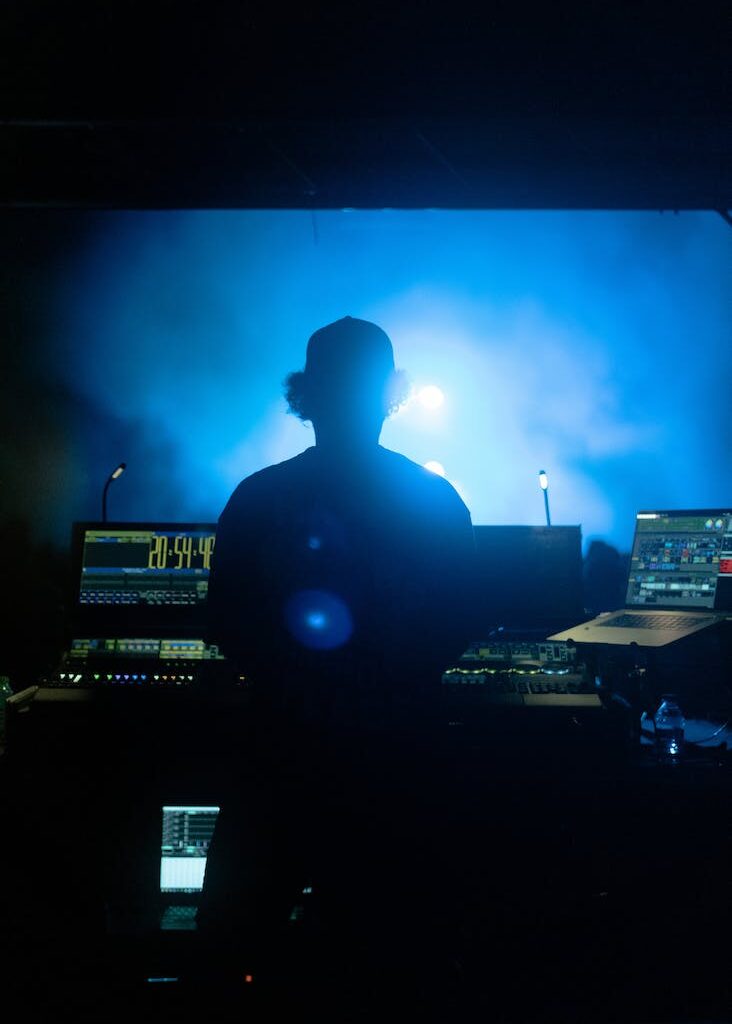 back view of a dj standing behind his console in a club