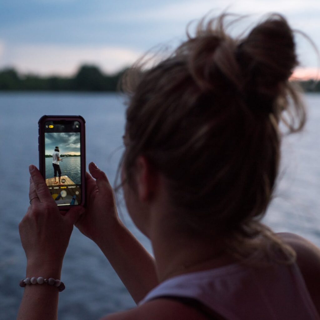 woman taking picture near water on mobile phone