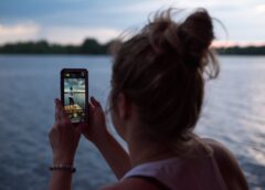 woman taking picture near water on mobile phone