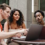 group of multiethnic coworkers discussing startup project on laptops together