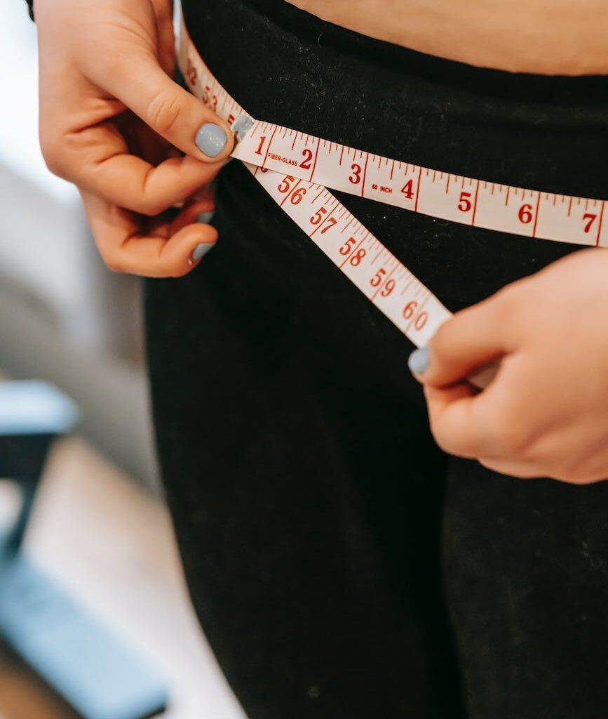 plus size woman measuring hips in gym