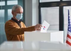 an elderly man dropping a paper in a ballot box